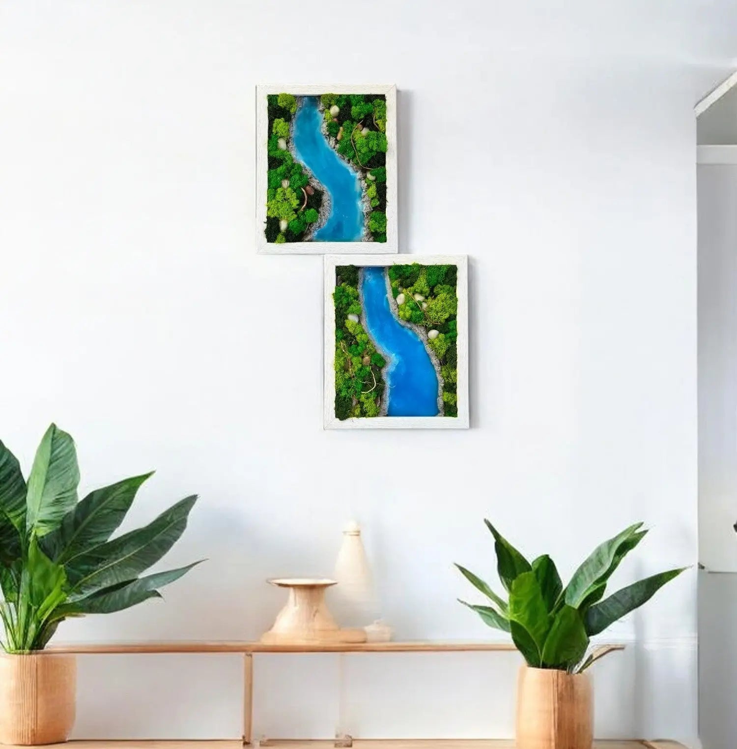 two wall decors contains variety of green color preserved moss with sky blue color epoxy resin and rock stones in rectangular shape hanging on the wall with plants and decorative items on shelfs and side tables 