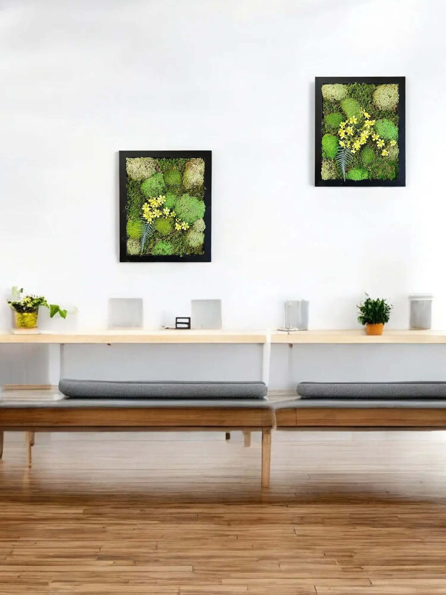 Preserved moss wall art hanging above a table with decorative plants on top