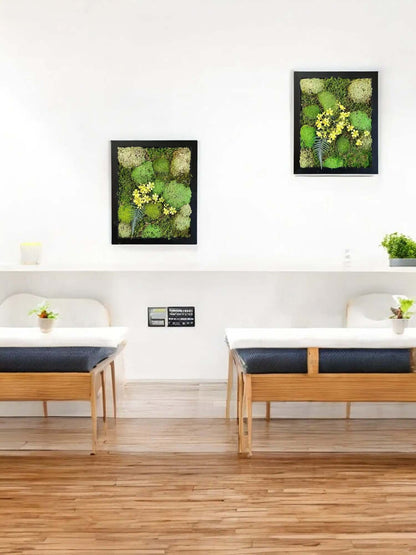 Preserved moss wall art hanging above a side table with decorative plants and home decor objects on top