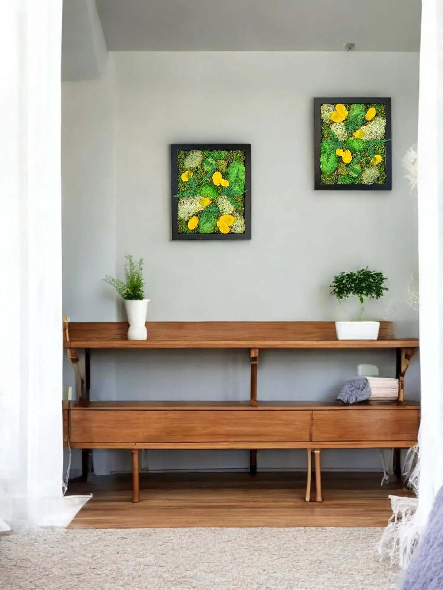 Preserved moss wall art hanging above a table with decorative plants on top in a bedroom