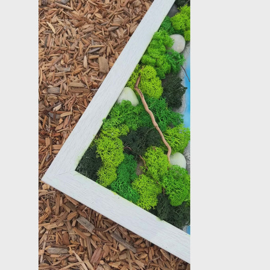 Video showcasing epoxy and moss wall art with a sky-blue epoxy river flowing through green moss and natural rocks.  Highlights the texture of the moss, the unique epoxy design, and the natural elements